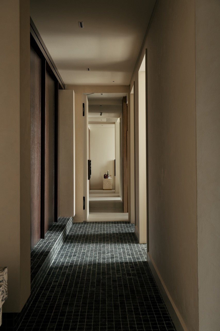 The long corridor, with mosaic flooring and custom handles, leads to the private bedroom areas