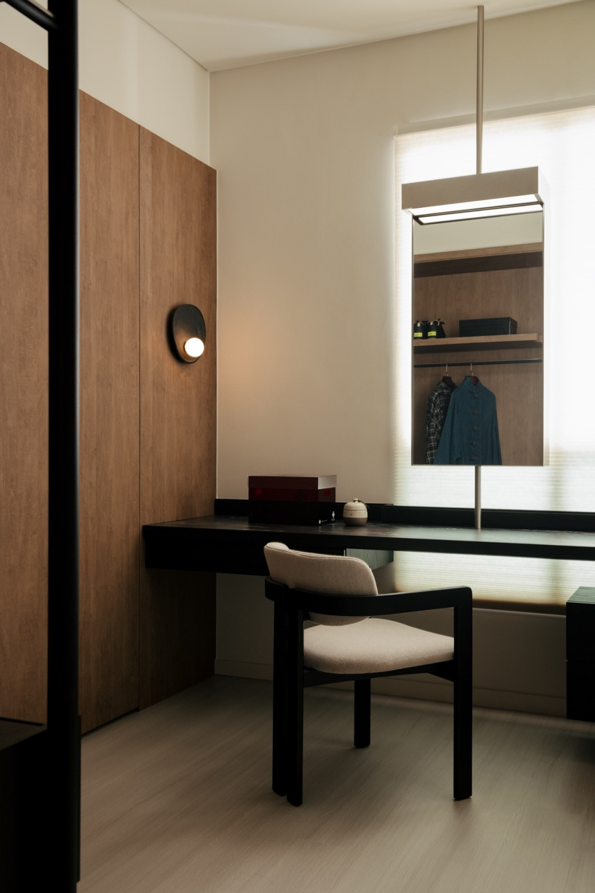 A dressing area with black furniture and concealed wardrobe storage sits within the master suite