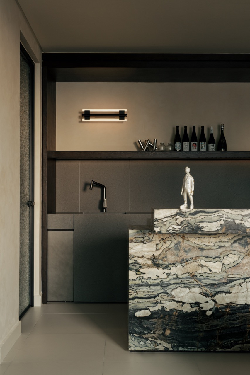The dry kitchen features jade green marble and Italian quartz cladding with black fixtures and walnut-toned cabinetry