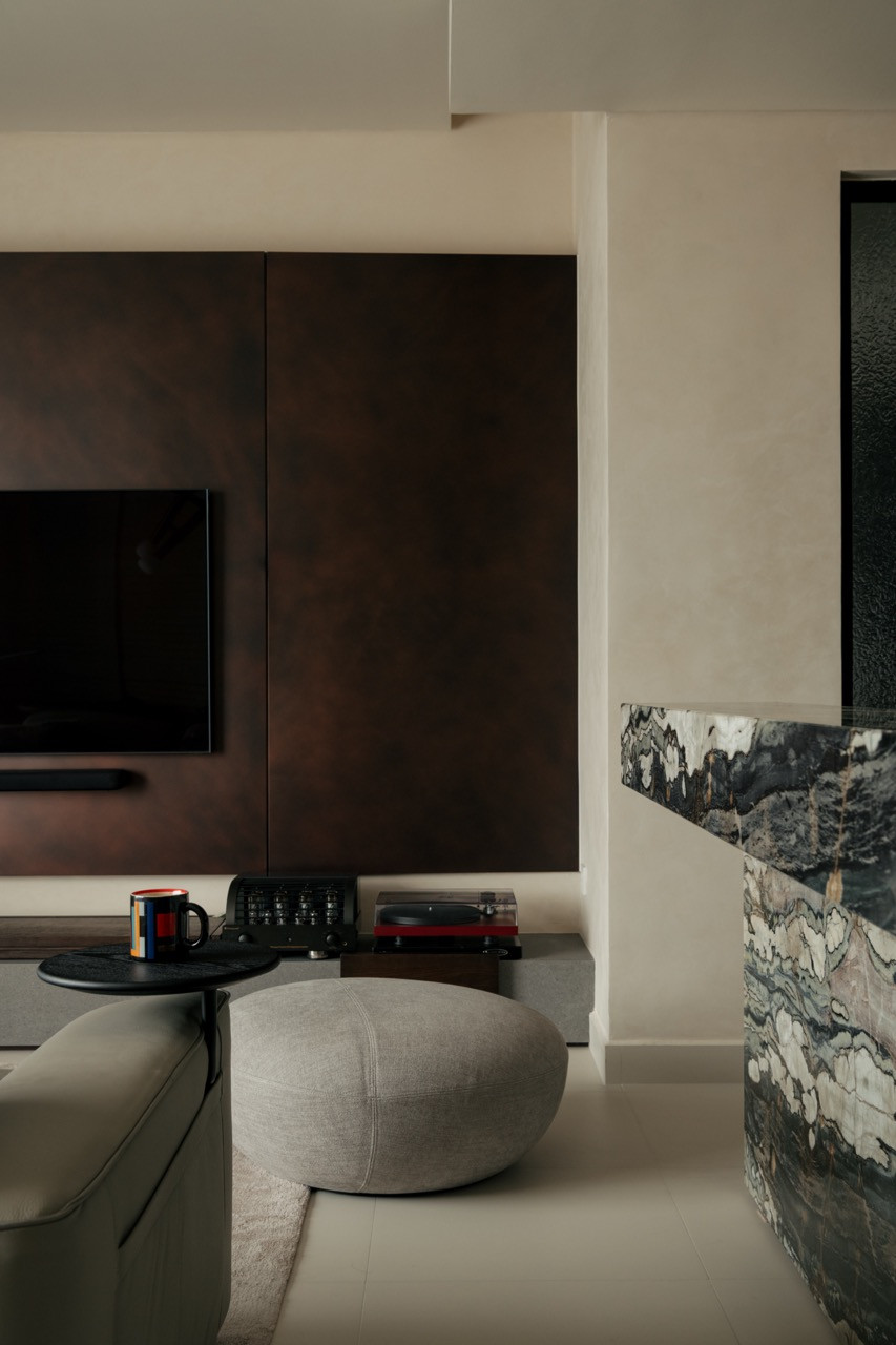 The living area’s TV backdrop uses a metal-effect finish in mild rustic copper with precise, restrained workmanship