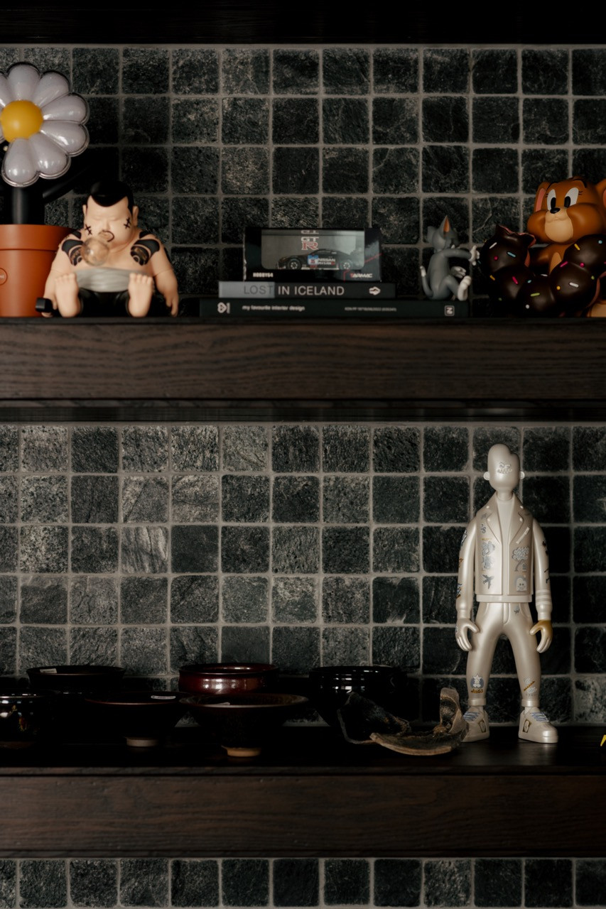 Open shelving displays Bob’s collection of vinyl records, toys and art against a backdrop of dark mosaic tiles
