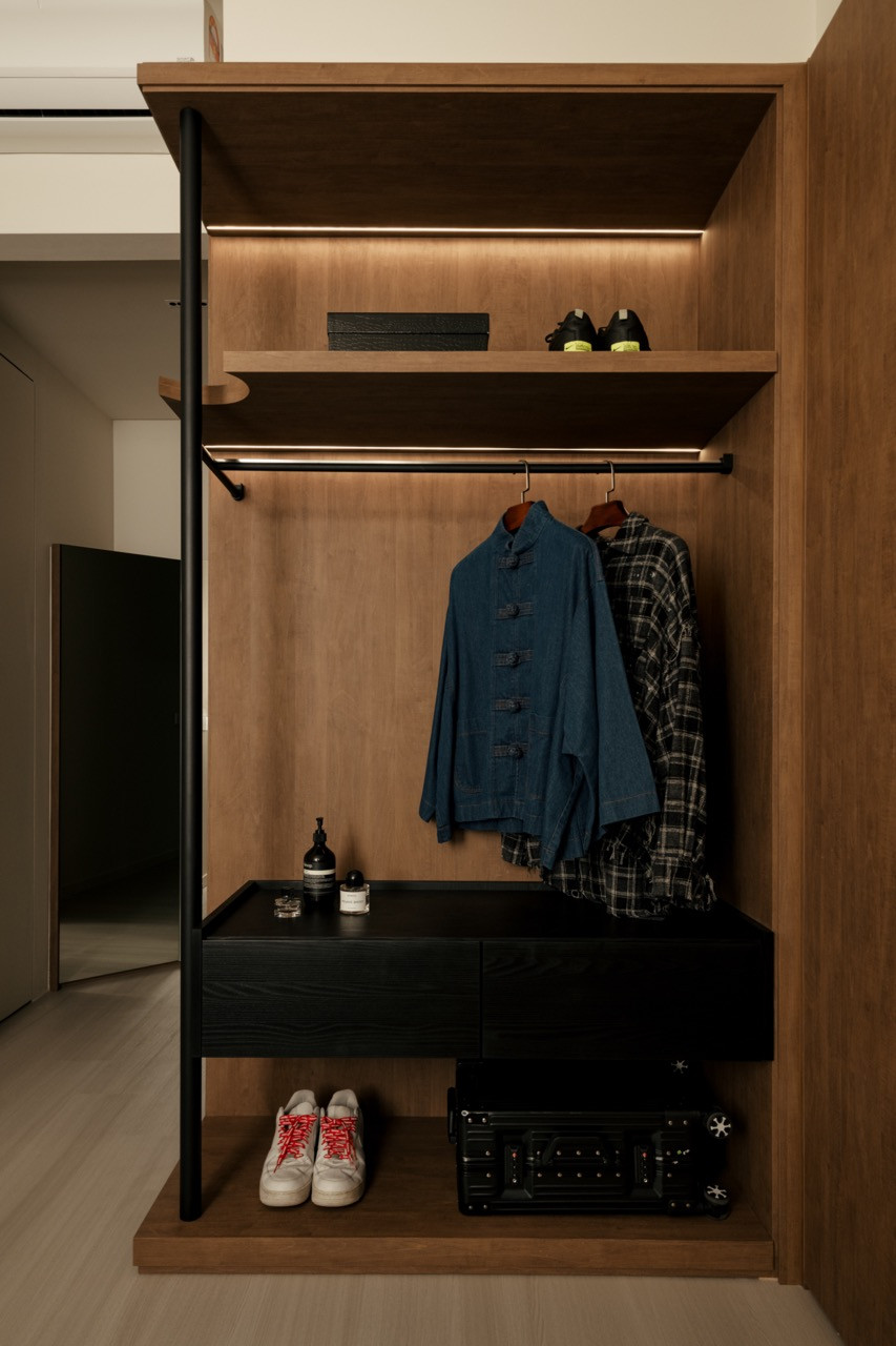 The custom walk-in wardrobe interior includes integrated lighting, hanging storage and drawer units finished in black