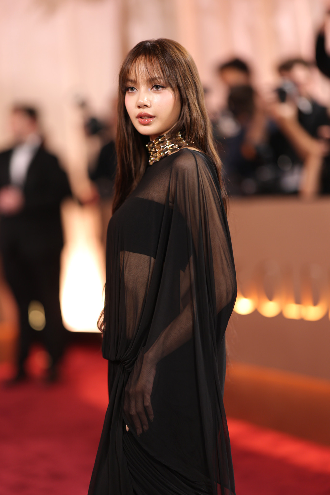 Lisa from Blackpink in a sheer black Jacquemus gown with stacked gold choker necklaces