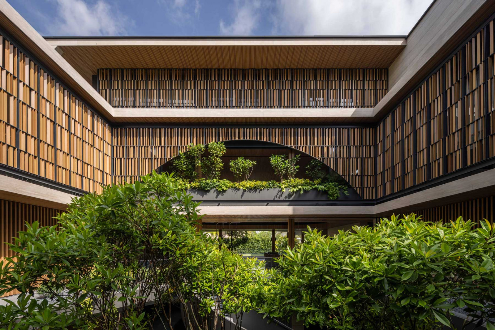 A breathtaking elevation reveals the Good Class Bungalow’s screen-clad façade emerging gracefully atop lush tropical greenery