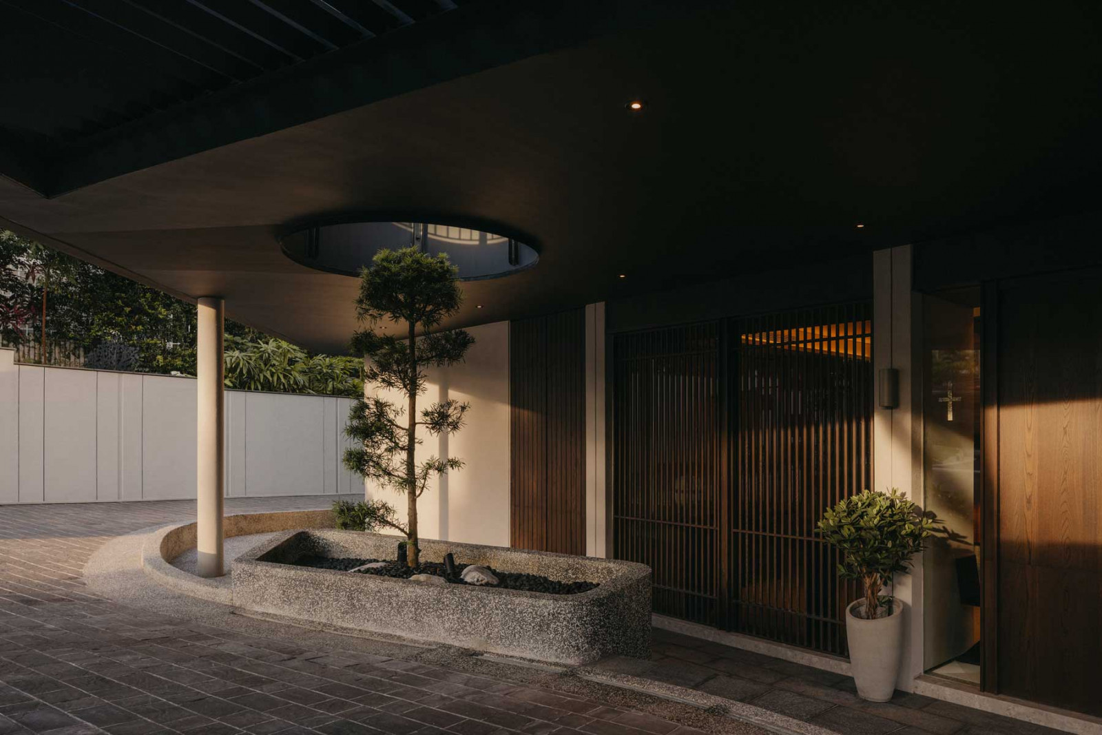 A circular opening in the second-storey balcony facilitates the growth of a pine tree on the ground floor