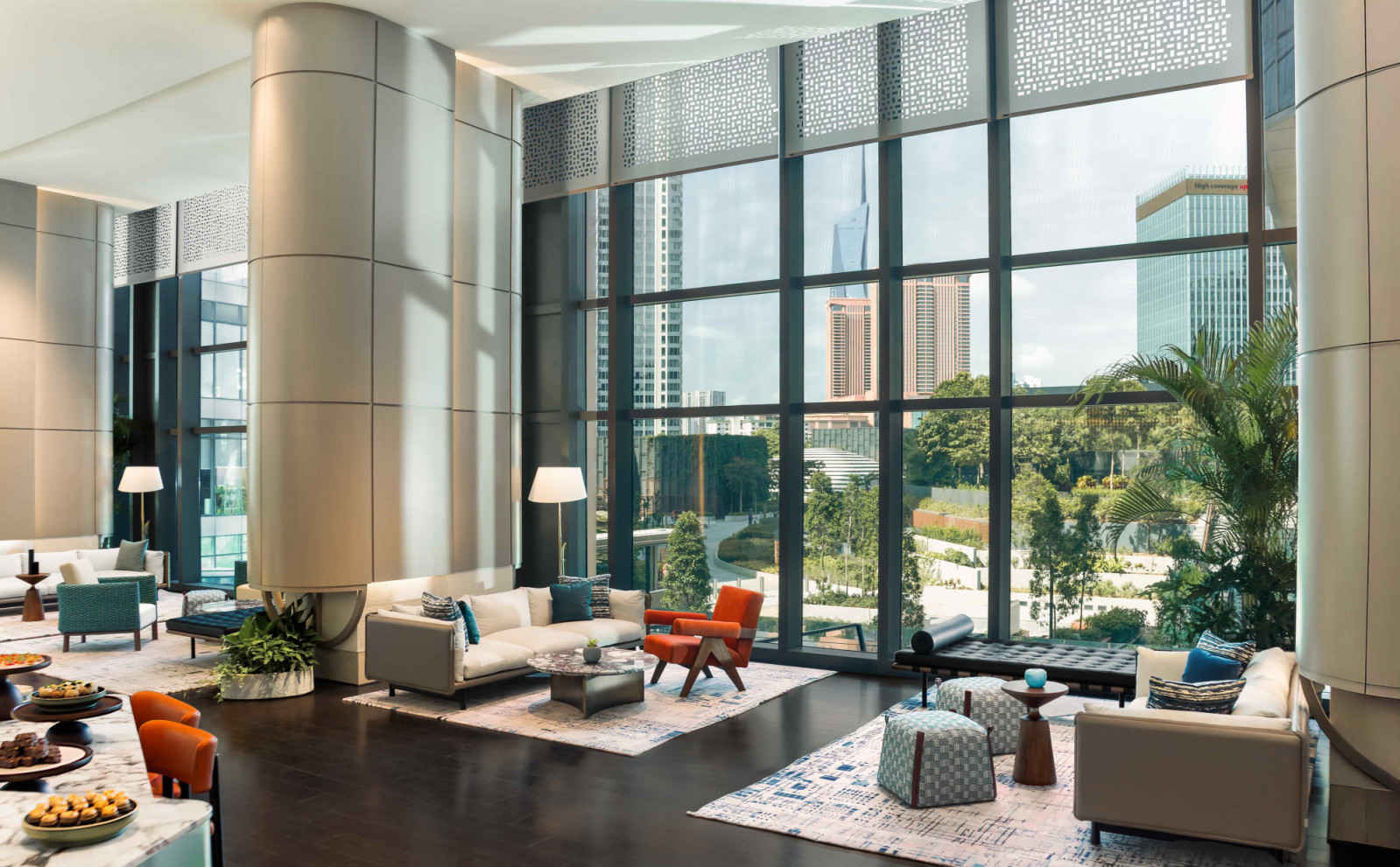 The open-plan lobby with soaring ceilings and floor-to-ceiling glazed windows overlooking the verdant TRX Park
