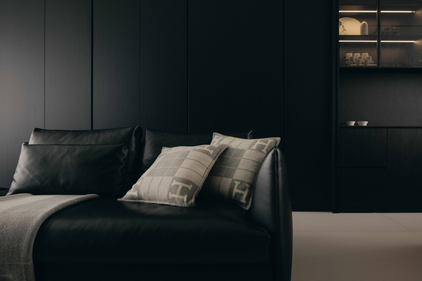 Light-toned cushions lend contrast to the black leather sofa