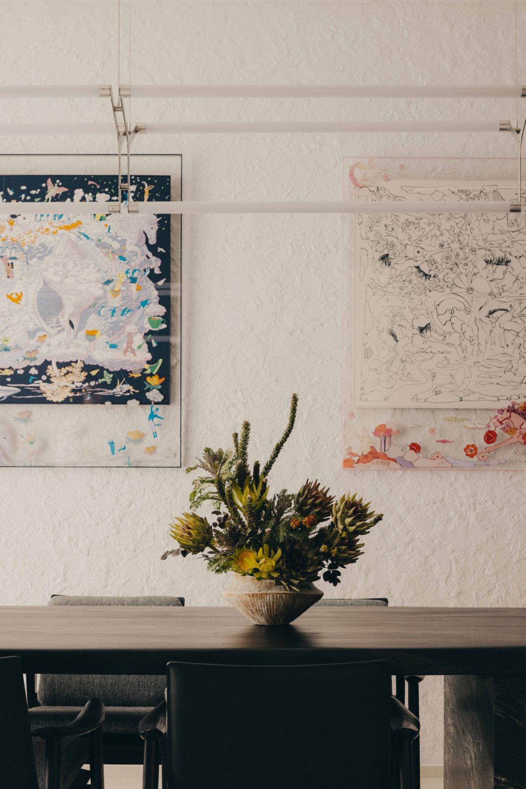 On one side of the apartment’s kitchen, a white wall showcases playful artworks, with a floral arrangement by Bunch & Branches in