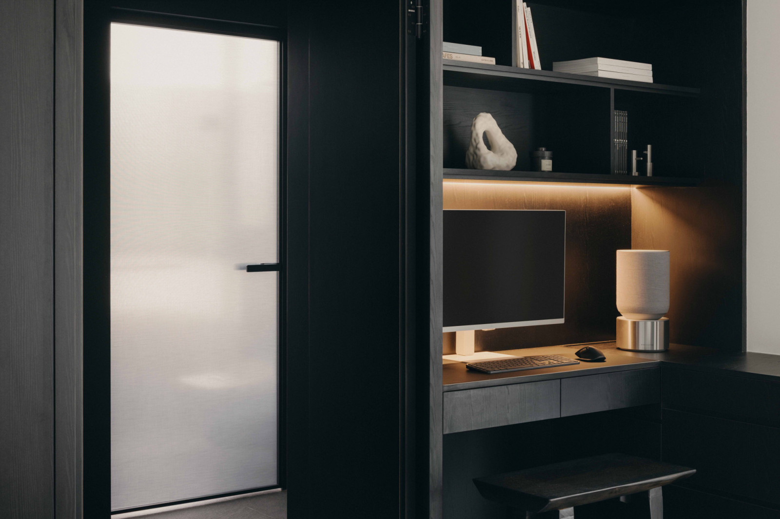 A gently lit study nook with overhead bookshelves