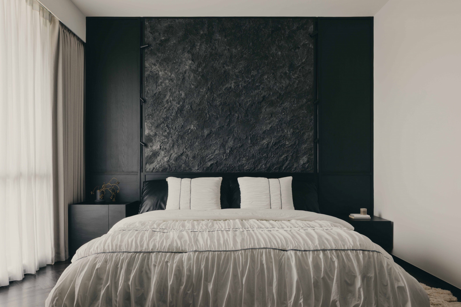 The master bedroom balances both light and dark finishes, with the textured panel above the bed acting as its focal point