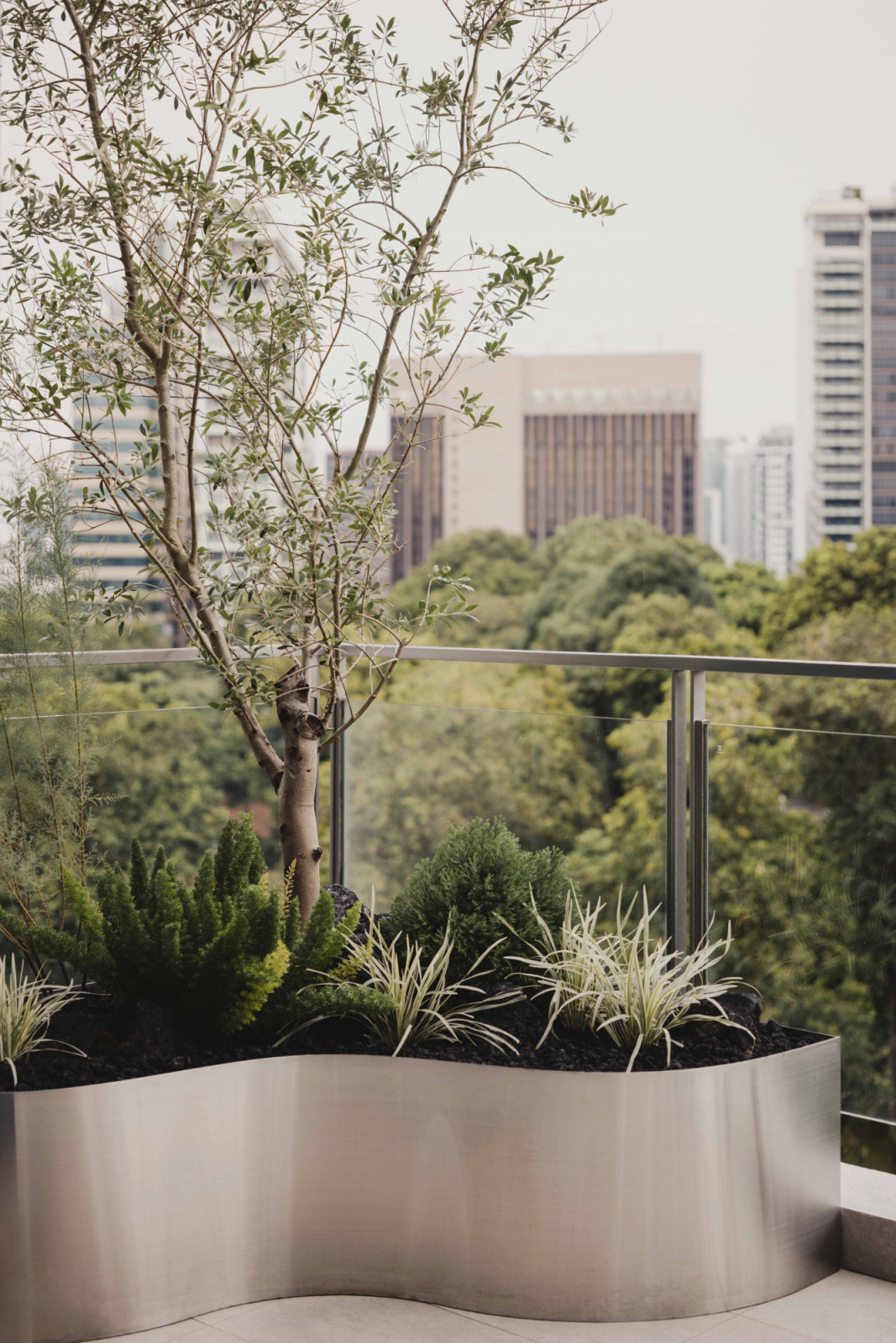 The balcony features a custom corner planter with curved edges that adds a touch of greenery