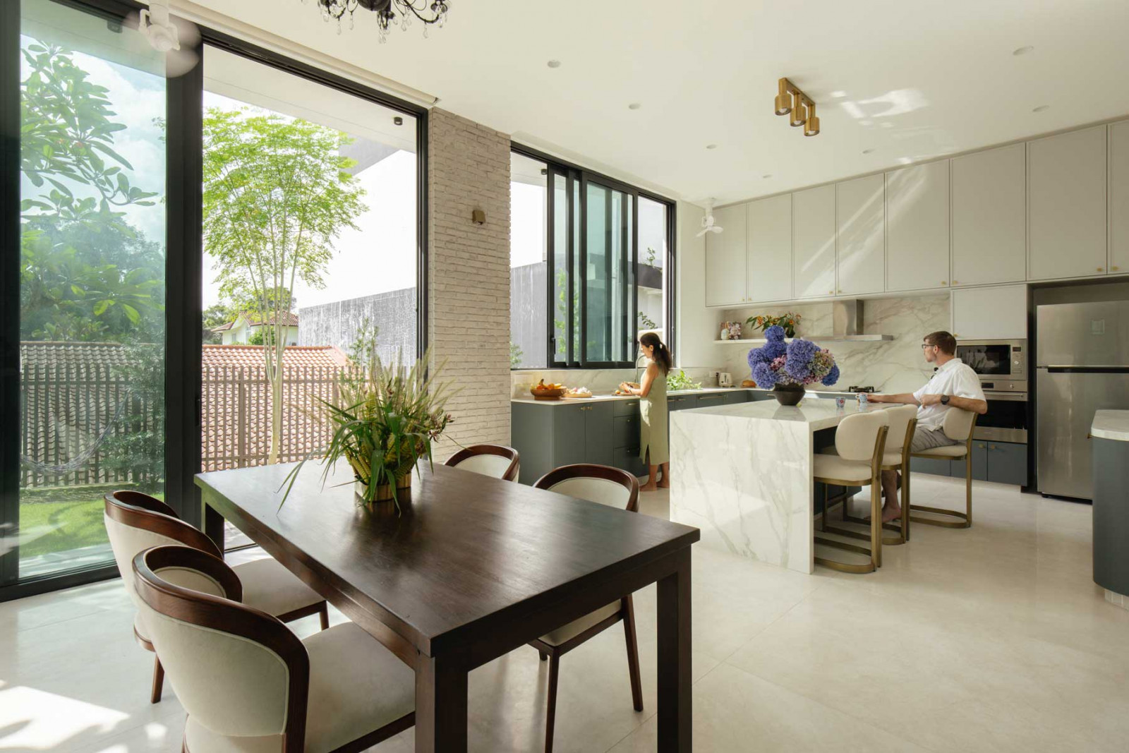 The dining area and kitchen enjoy a seamless connection to the outdoors via large openings and expansive glazing