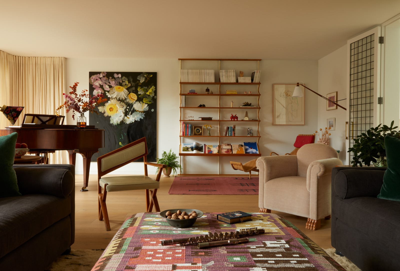Neutrals made infinitely more interesting through the use of unusual pairings, such as contrasting chairs situated behind a patterned ottoman; further behind, in the background, a light shelf lends a certain legerity as it is flanked by a piano and a chaise lounge in Beata Heuman's home