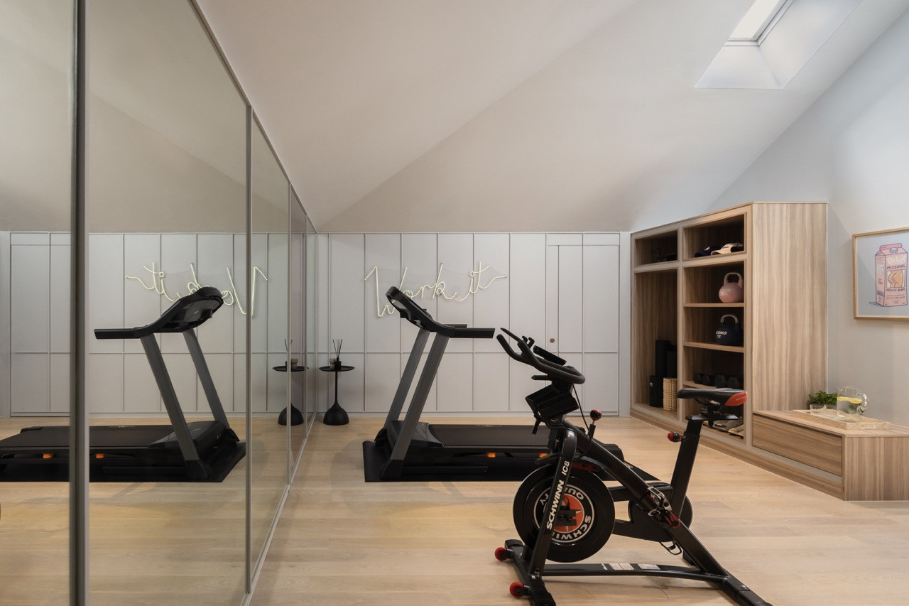 Phòng gym chiếm một phần không gian của tầng áp mái mở rộng, gây ấn tượng với hệ trần vòm cao vút và cửa sổ trời (skylight) đón ánh sáng tự nhiên. Việc kết hợp thêm các mảng tường ốp gương giúp tối đa hóa cảm giác về sự thông thoáng và chiều sâu cho khu vực tập luyện.