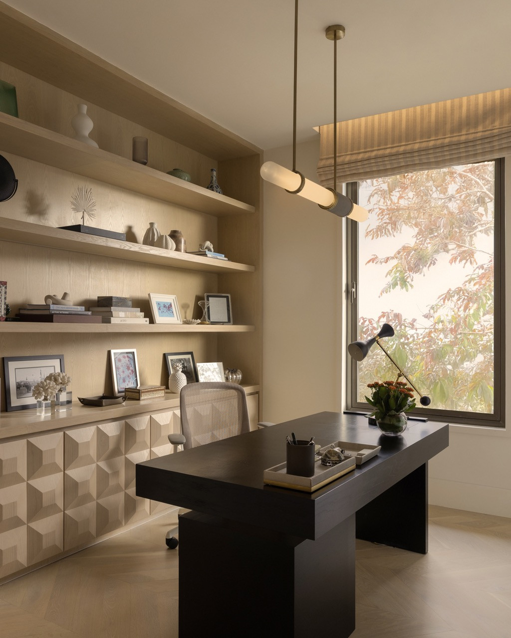 The study includes floor-to-ceiling shelving with integrated LED lighting and a geometric three-dimensional panel treatment on the base