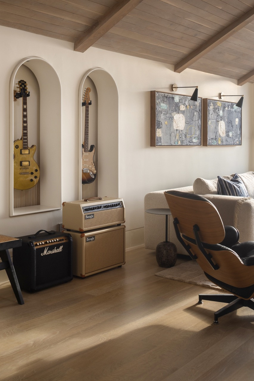 Không gian "mancave" mang đậm dấu ấn cá nhân với hệ hốc tường hình vòm được thiết kế riêng để trưng bày bộ sưu tập guitar, bên cạnh các tác phẩm nghệ thuật đương đại và chiếc ghế Eames Lounge Chair kinh điển.