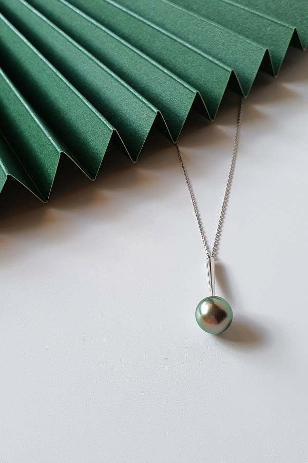 A Tahitian pearl with a greenish gray bodycolour and subtle pink overtones, displaying the highly sought-after peacock hue