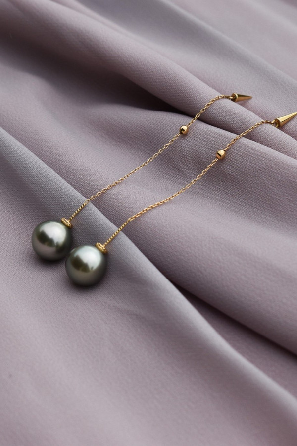 A pair of Tahitian pearl earrings with exceptional lustre, reflecting the surrounding environment with remarkable clarity