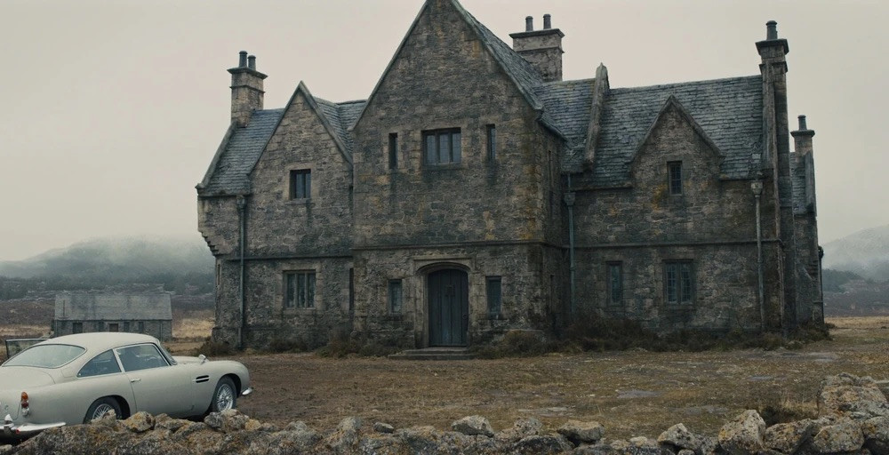 Skyfall Lodge with Bond’s Aston Martin DB5. Art director Dean Clegg designed the set, built from plywood and plaster at Hankley Common in Surrey, to resemble Highland vernacular architecture with weathered stone and moss-covered walls