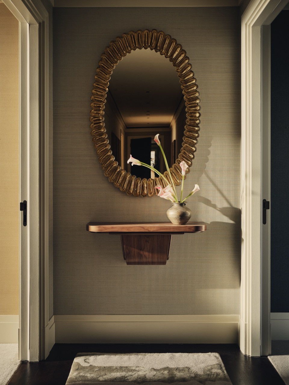 A corridor detail showing the layered approach to materials, including timber, brass and decorative objects