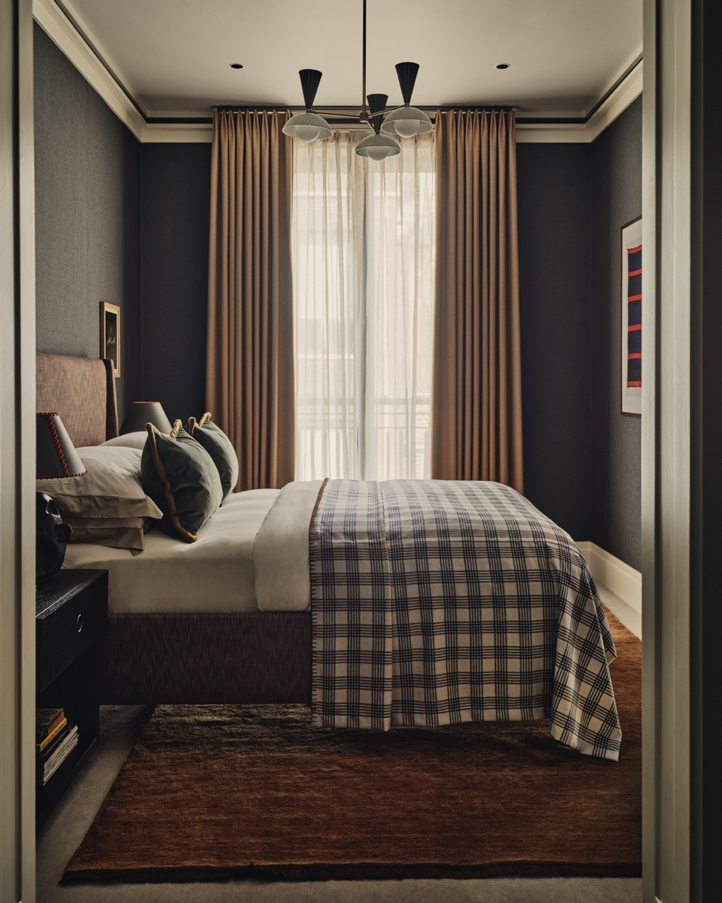 A bedroom featuring dark grasscloth walls and a plaid throw, showing Bense's approach to creating contrast
