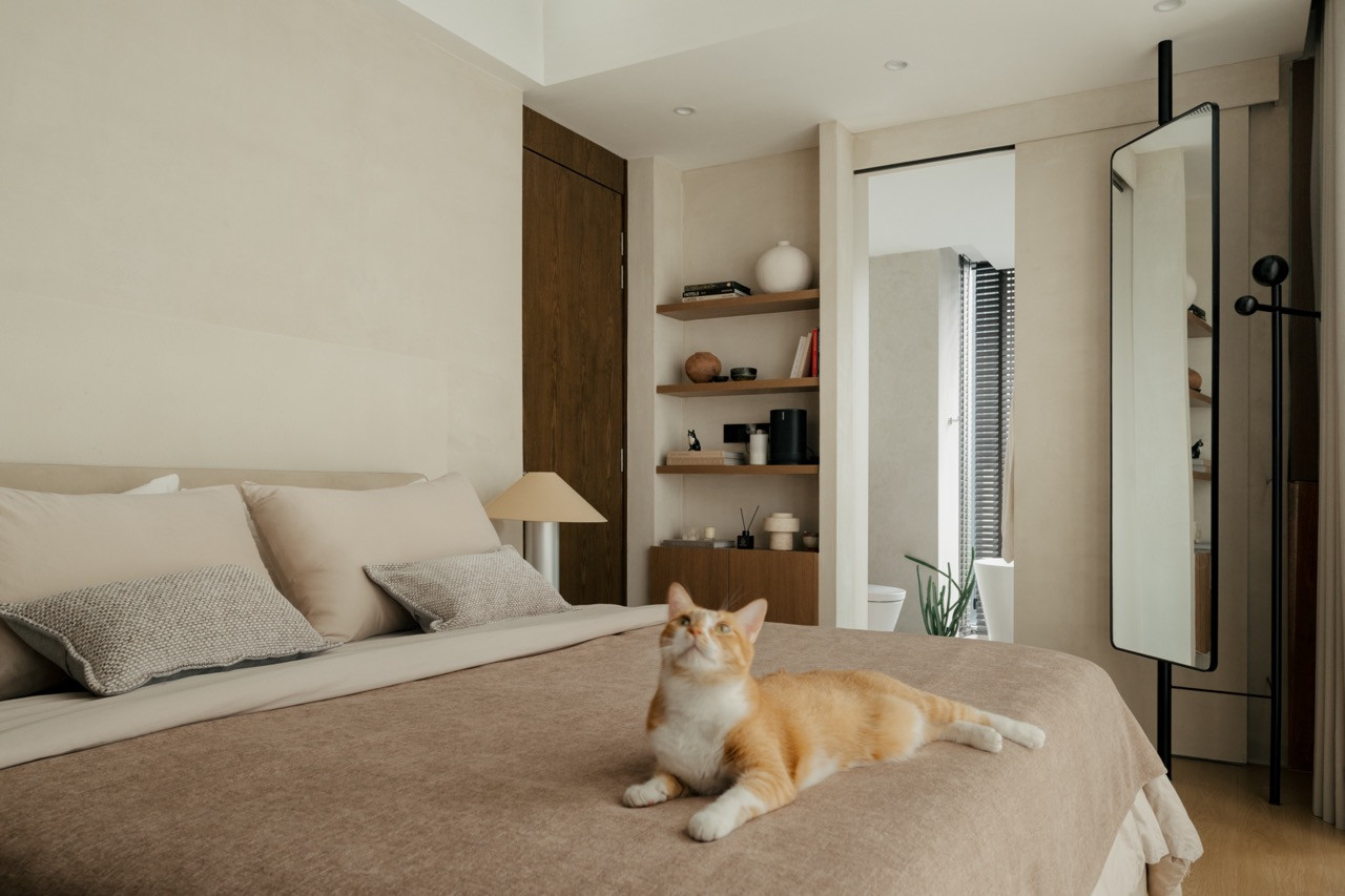 The client’s cat is on the bed, with views to the ensuite and built-in timber shelving