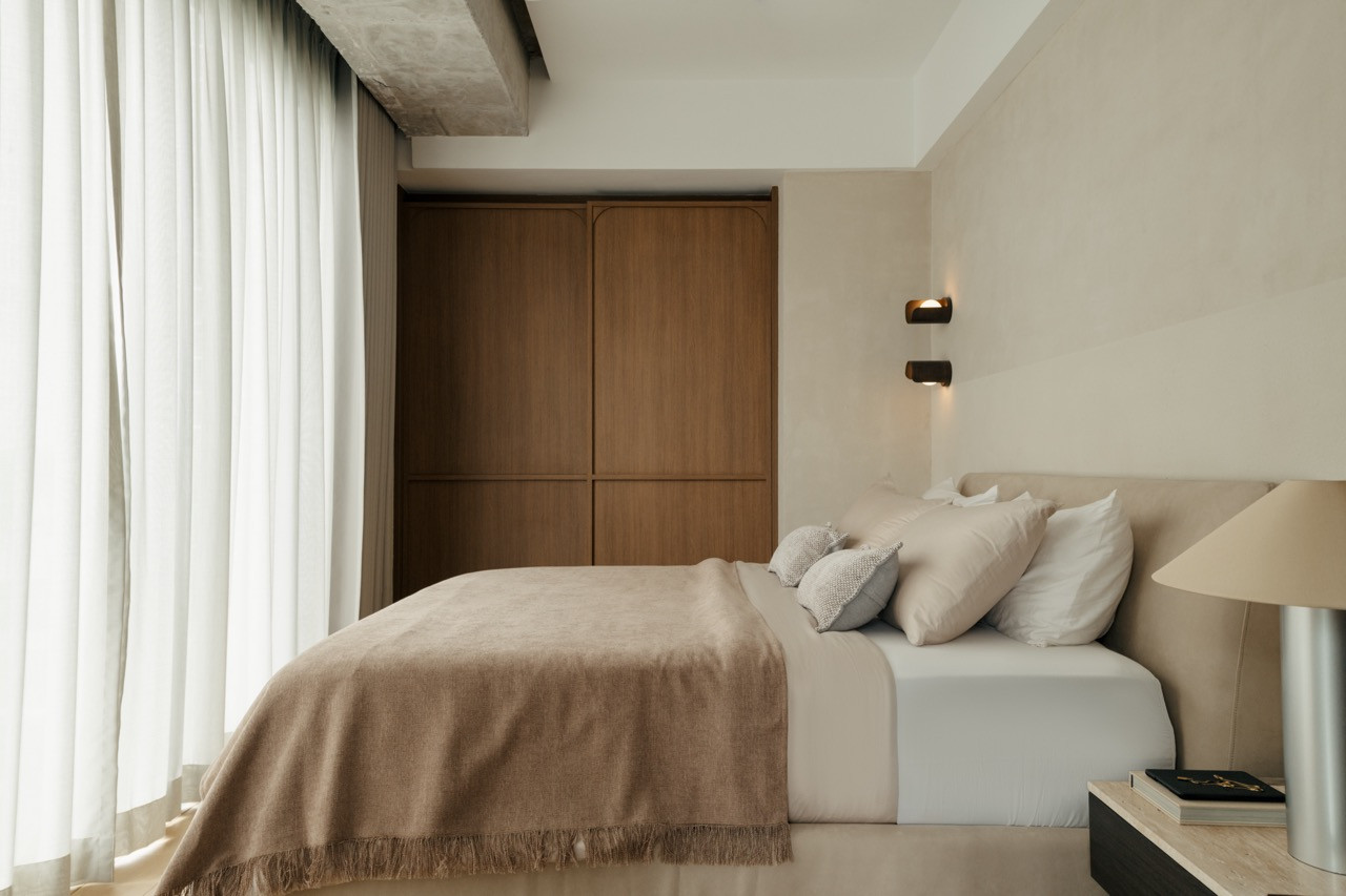 Primary bedroom with floor-to-ceiling curtains and timber wardrobes in the double-volume space