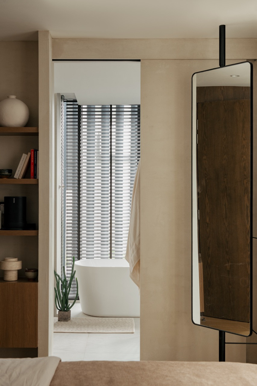 View from the bedroom to the ensuite bathroom, with timber shelving displaying minimal objects