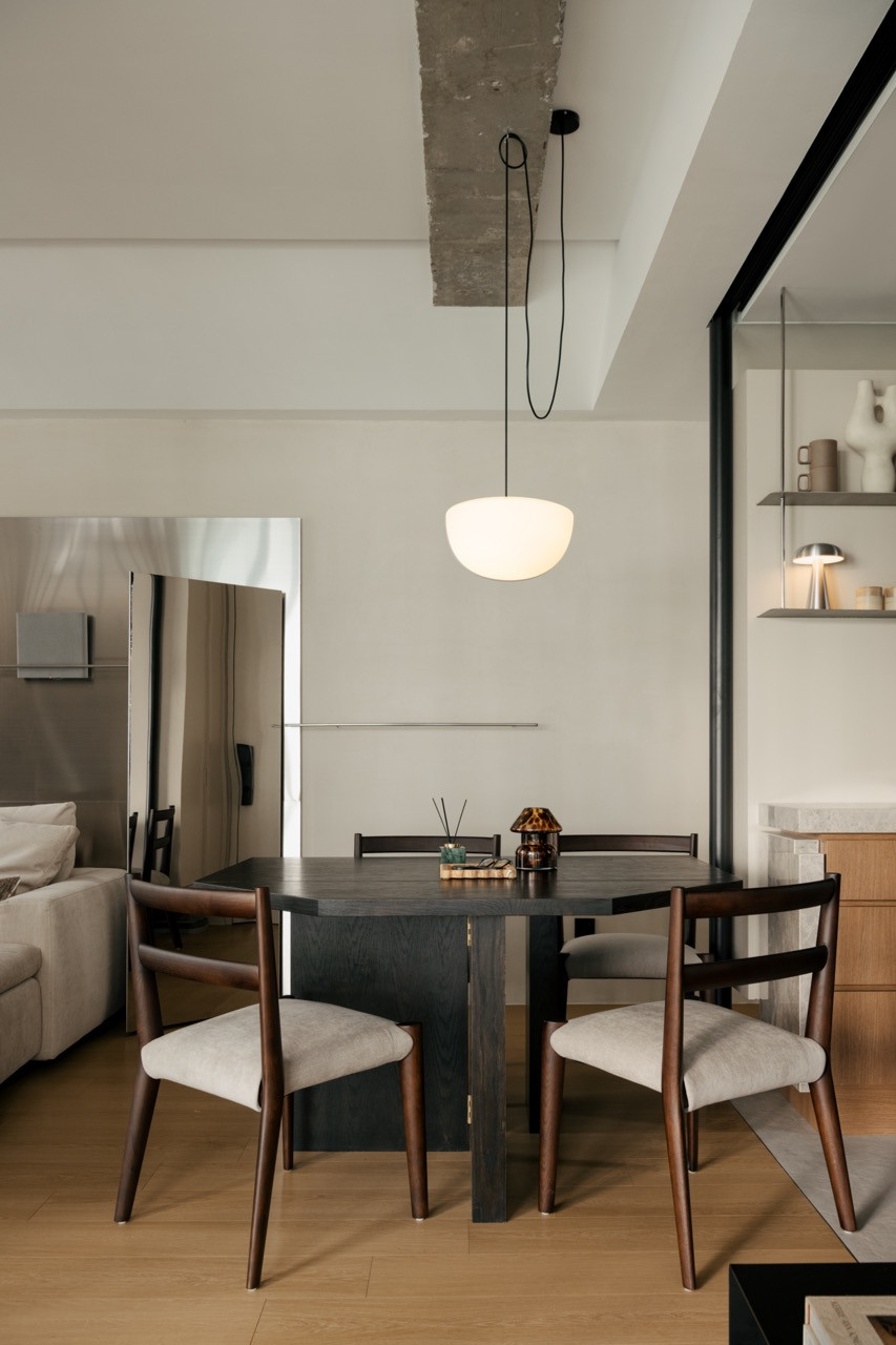 Dining table with dark timber and stone finishes, black pendant light above
