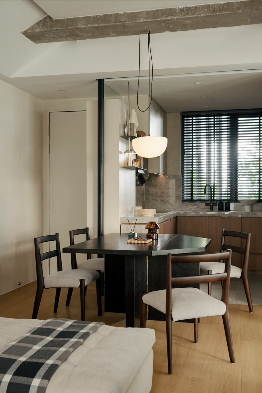 Dining area with black and timber chairs, pendant light hanging from exposed concrete beam