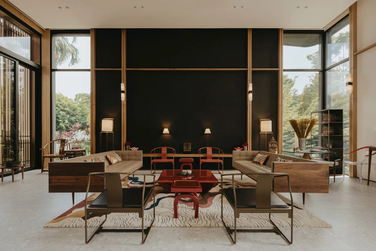 The red-finished furniture pieces at the centre of Good Class Bungalow’s second-floor living room create a striking contrast against the black wall