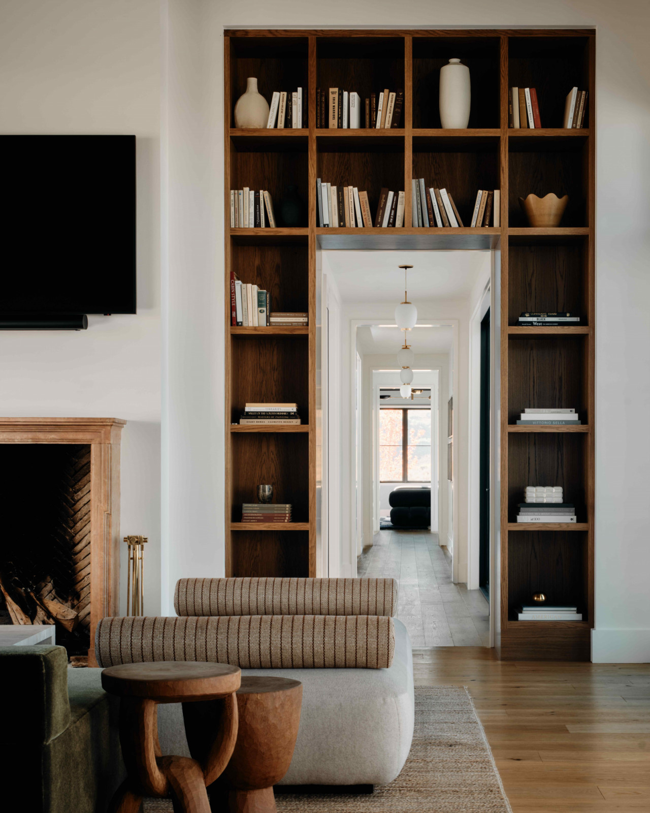 Walnut bookcases recessed into the wall flanking the fireplace and TV