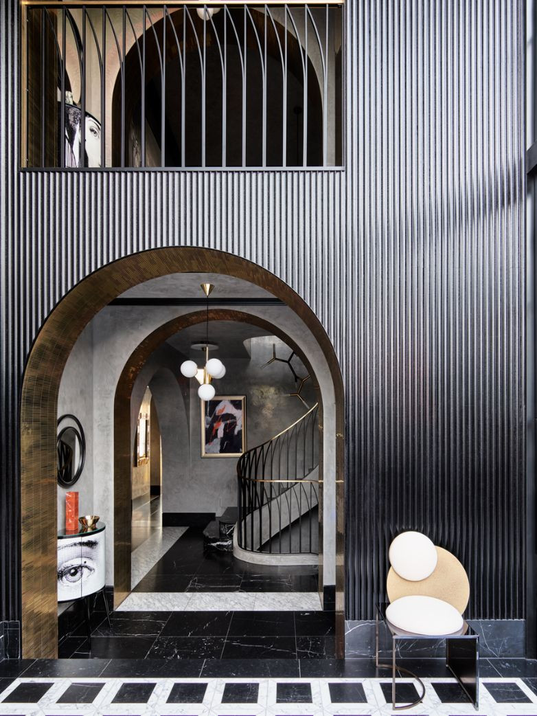 An Occi console from Fornasetti peeks at visitors in the entryway, while echoing the curvature of the arched portals, the Tom Dixon Plane short chandelier and the Celeste chair by Lara Bohinc (Photo: Anson Smart)