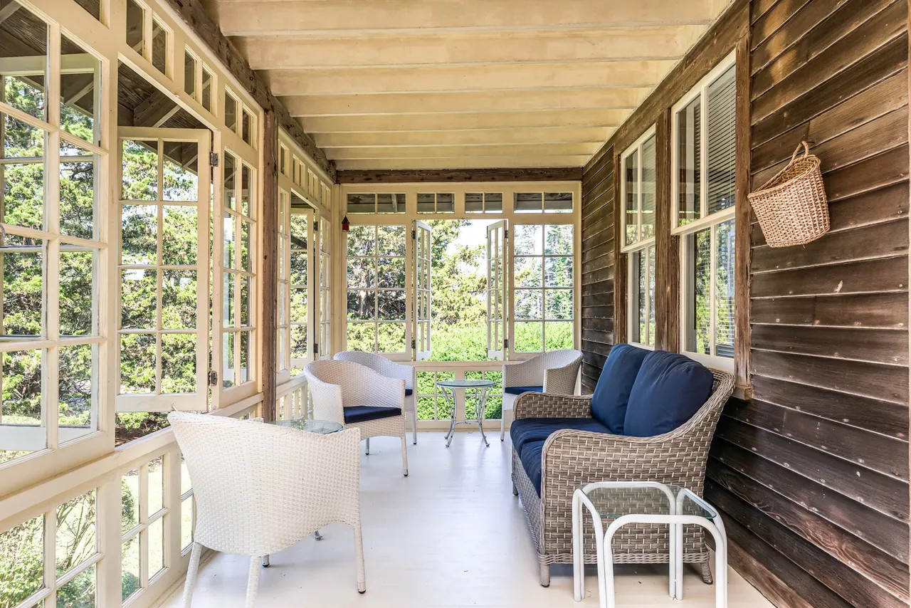 A light-filled sunroom at the historic Rhode Island estate, featuring floor-to-ceiling windows and classic coastal decor for an indoor-outdoor feel. (Source: realtor.com)