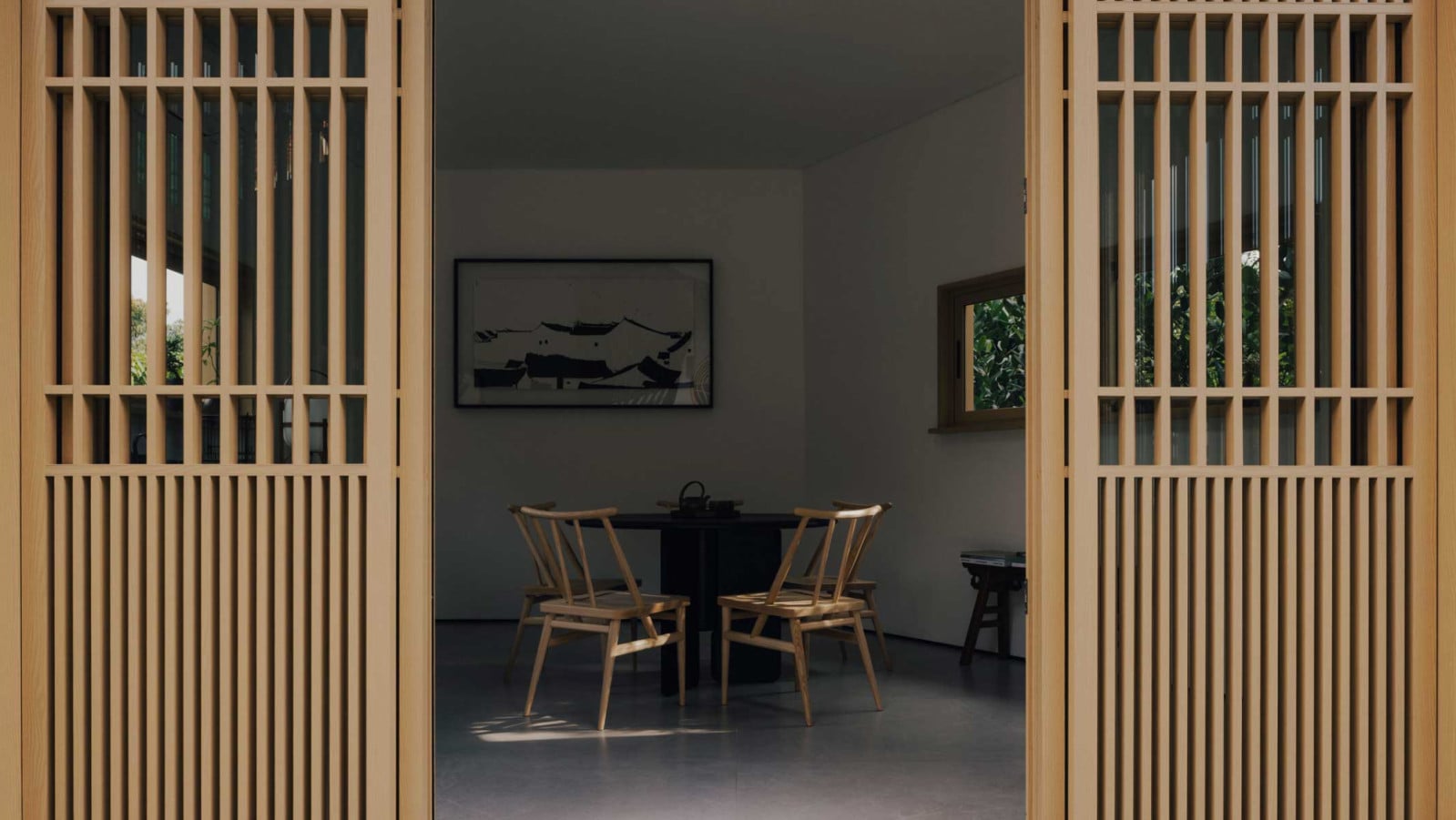 A well-curated interior of the tea room in this Bukit Timah home peeks through sliding doors articulated with timber detailing inspired by birdcages