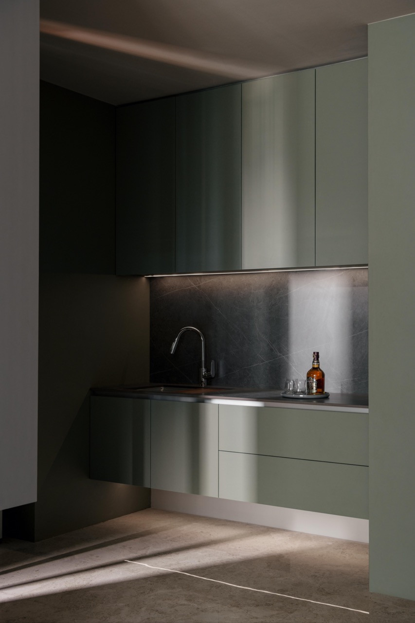 The man cave’s wet bar features sage-green cabinetry and a Black Marquina marble backsplash
