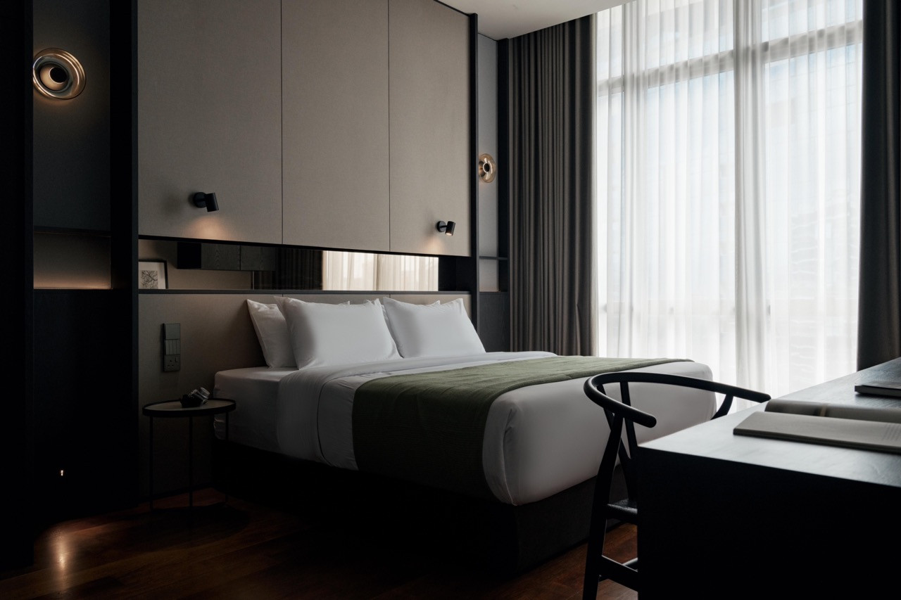 The master bedroom balances taupe panels with dark timber and brushed Chardonnay gold overhead cabinetry