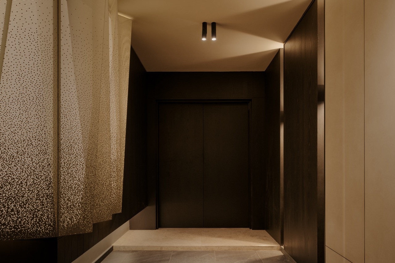 The main entrance with dark ebony-stained timber panels and the origami light installation visible beyond