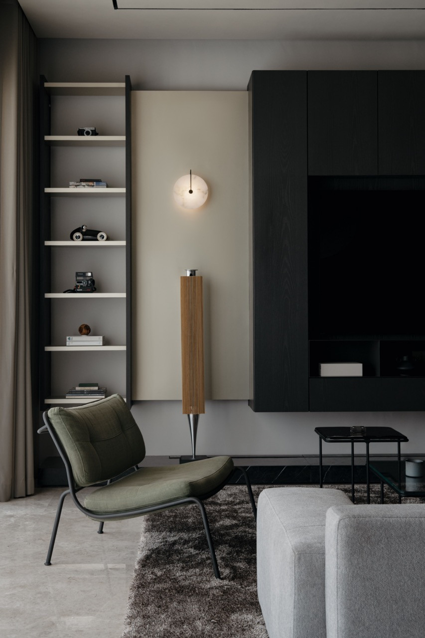 A Beolab 18 sound column by B&O stands beside custom-built-in shelving with concealed lighting