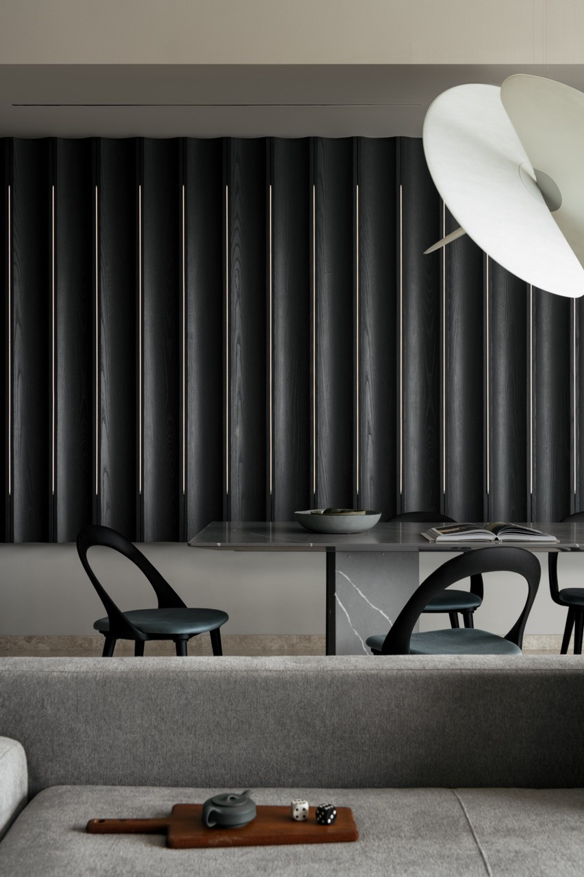 The Levante pendant by Luceplan hangs above the dining table with dark fluted panels beyond