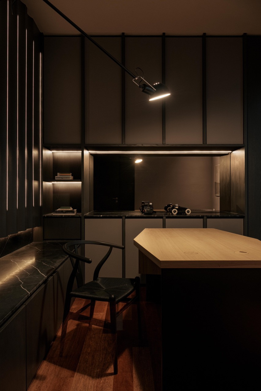 Dark timber panels wrap the home office with a 265 Small wall lamp above the Wishbone chair