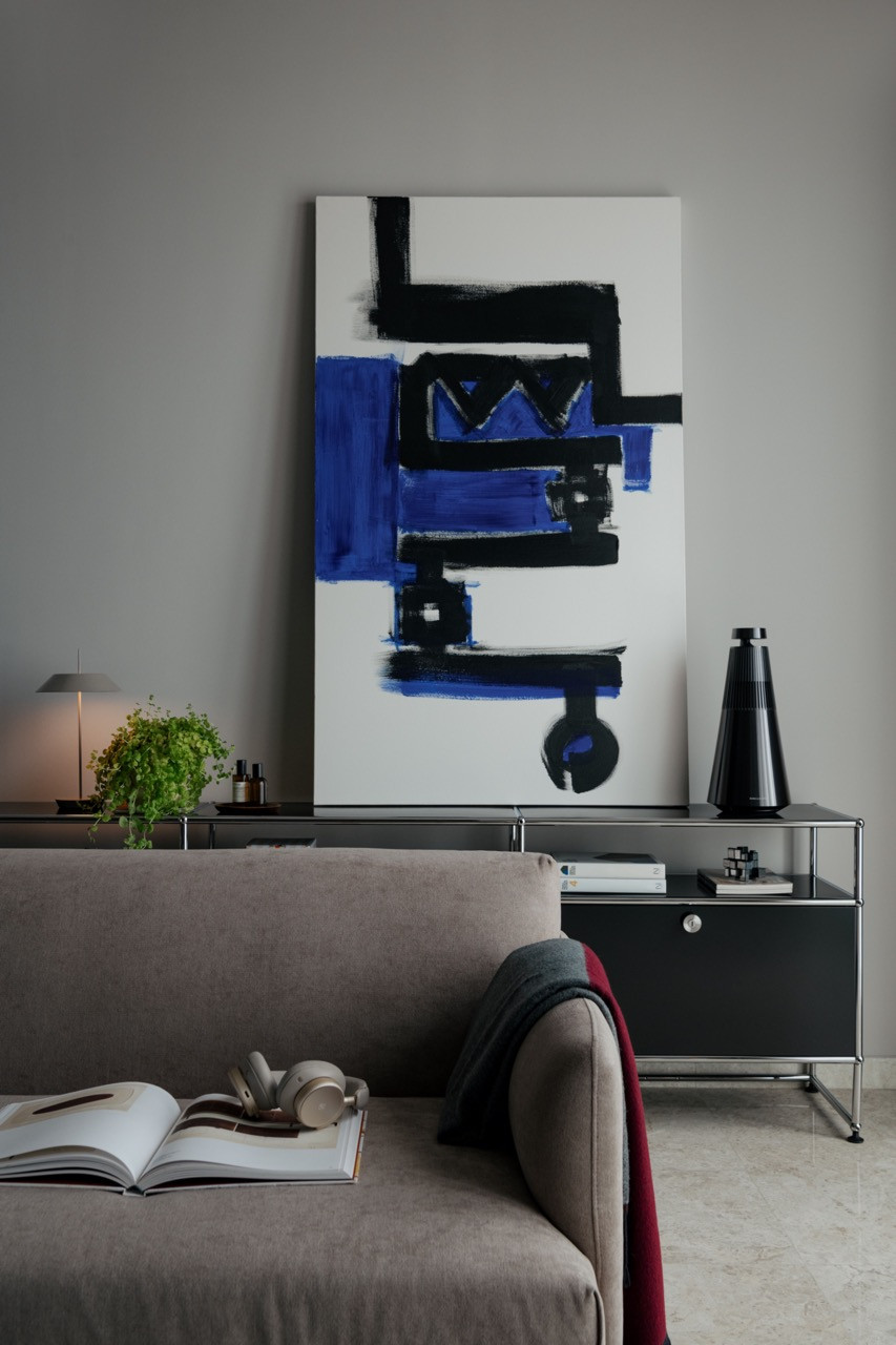 A Haller Low Cabinet by USM beneath abstract artwork, with a Mayfair Mini pendant by Vibia