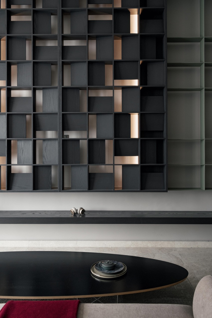 Floor-to-ceiling grid shelving in dark ebony-stained ash veneer with integrated lighting