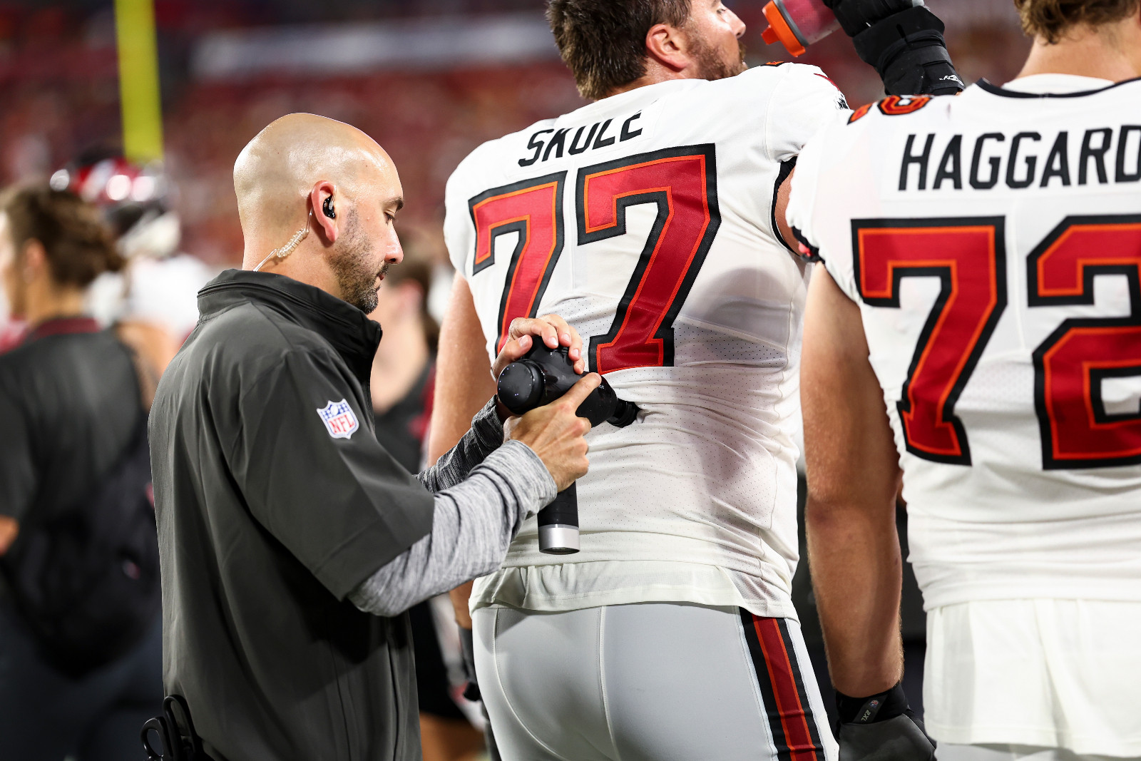 A trainer uses a massage gun on an NFL player during a preseason game (Photo: Getty Images)