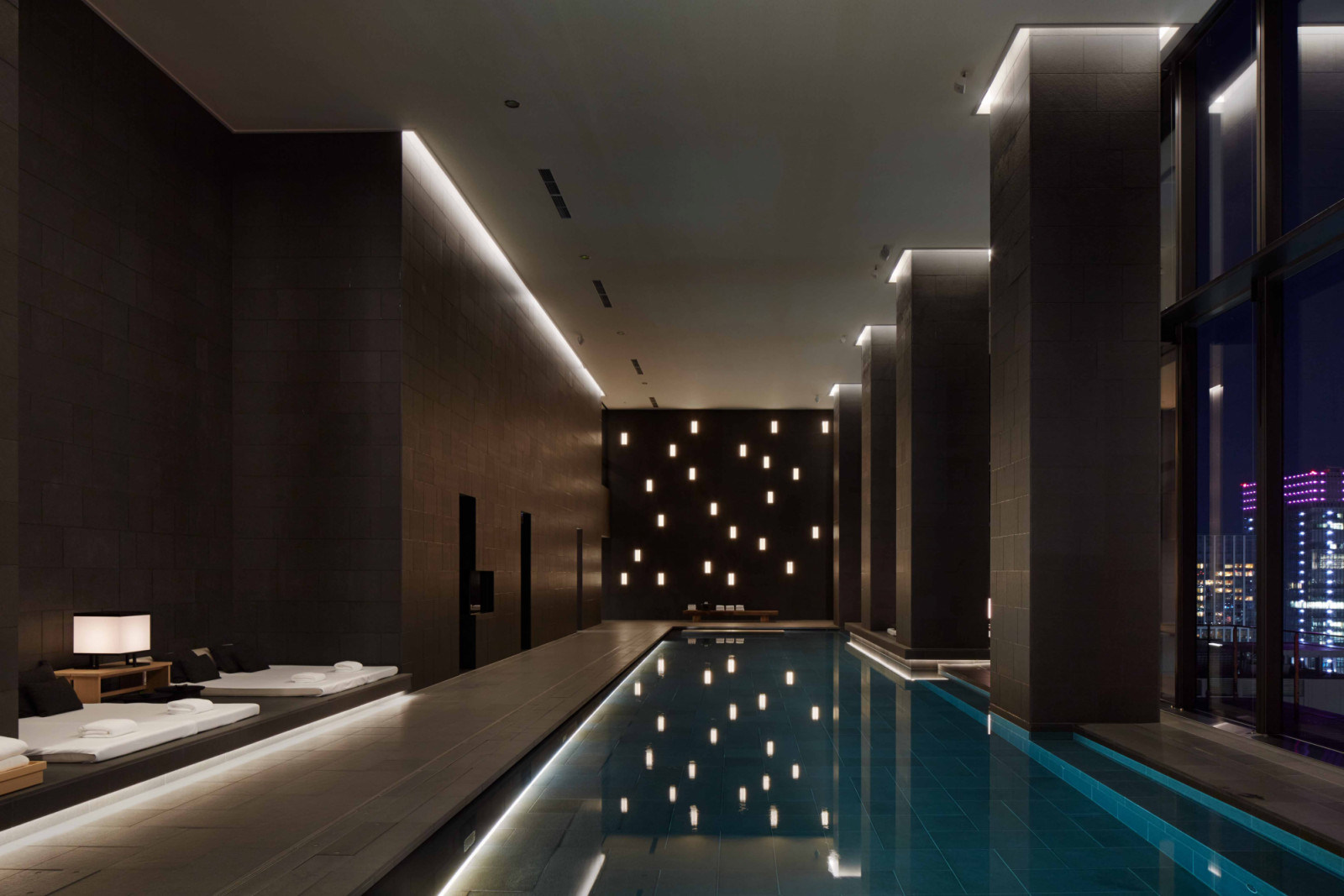 As evening falls, softened interior lighting transforms the pool into a quiet sanctuary