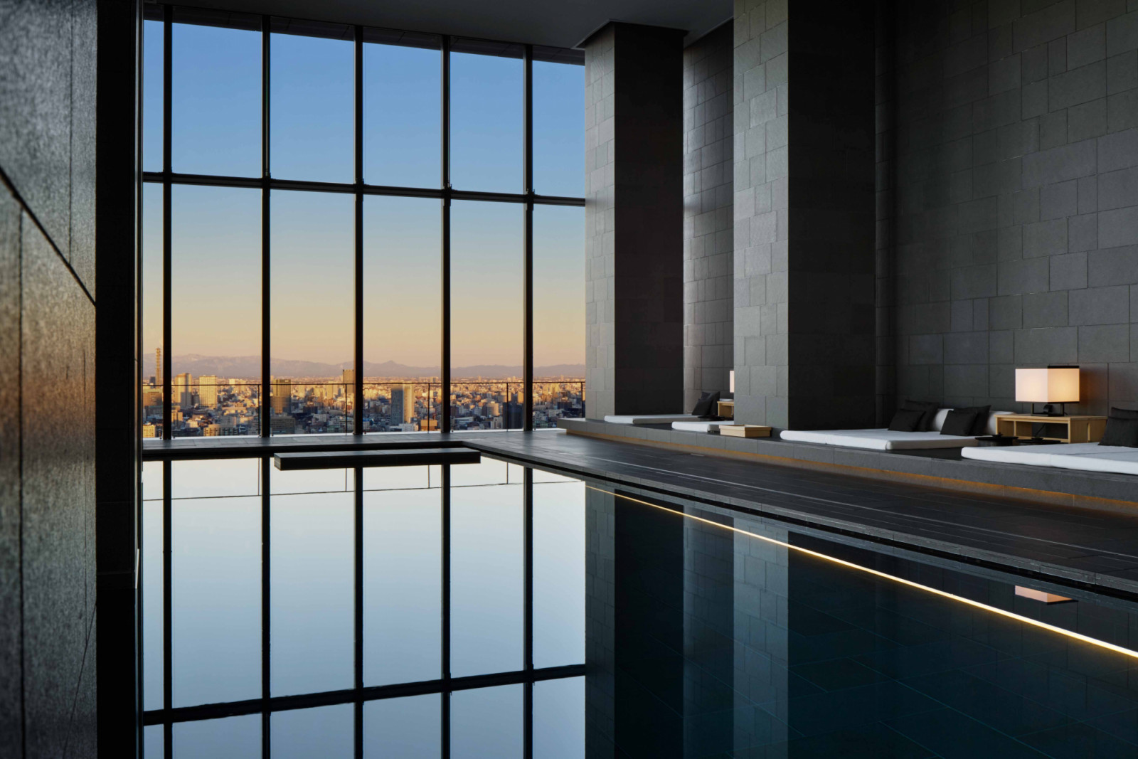 views towards Tokyo Skyline at dusk when the pool captures the changing colours of the sky, with warm light dissolving into water