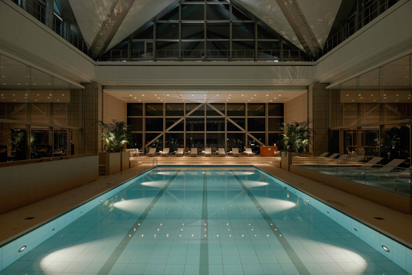 In the evening, softened lighting and the glow of the city skyline transform the pool into an intimate, cinematic retreat high above Tokyo