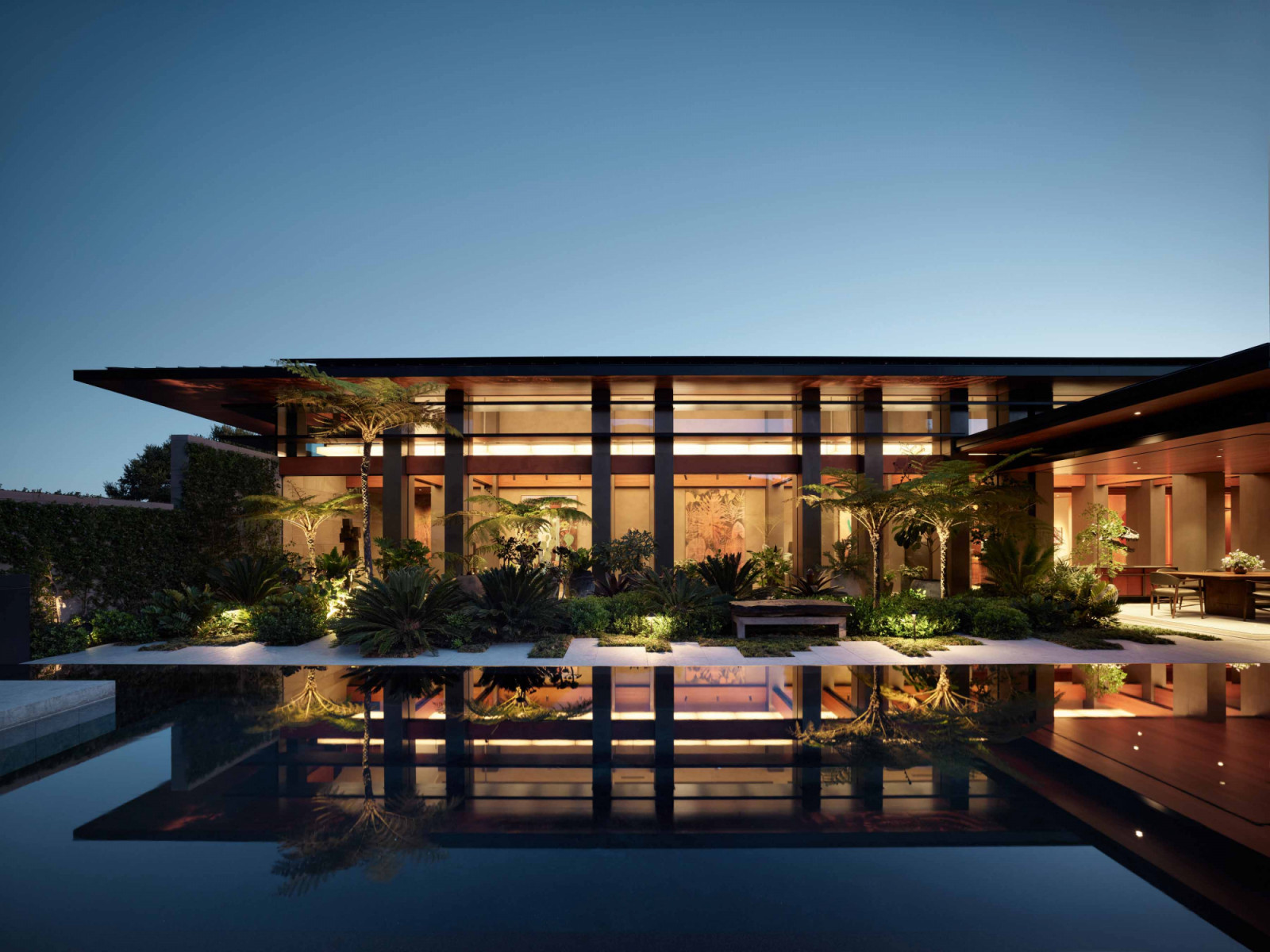 A perspective of the Infinity House at twilight, reflected beautifully in the shallow pool that surrounds it