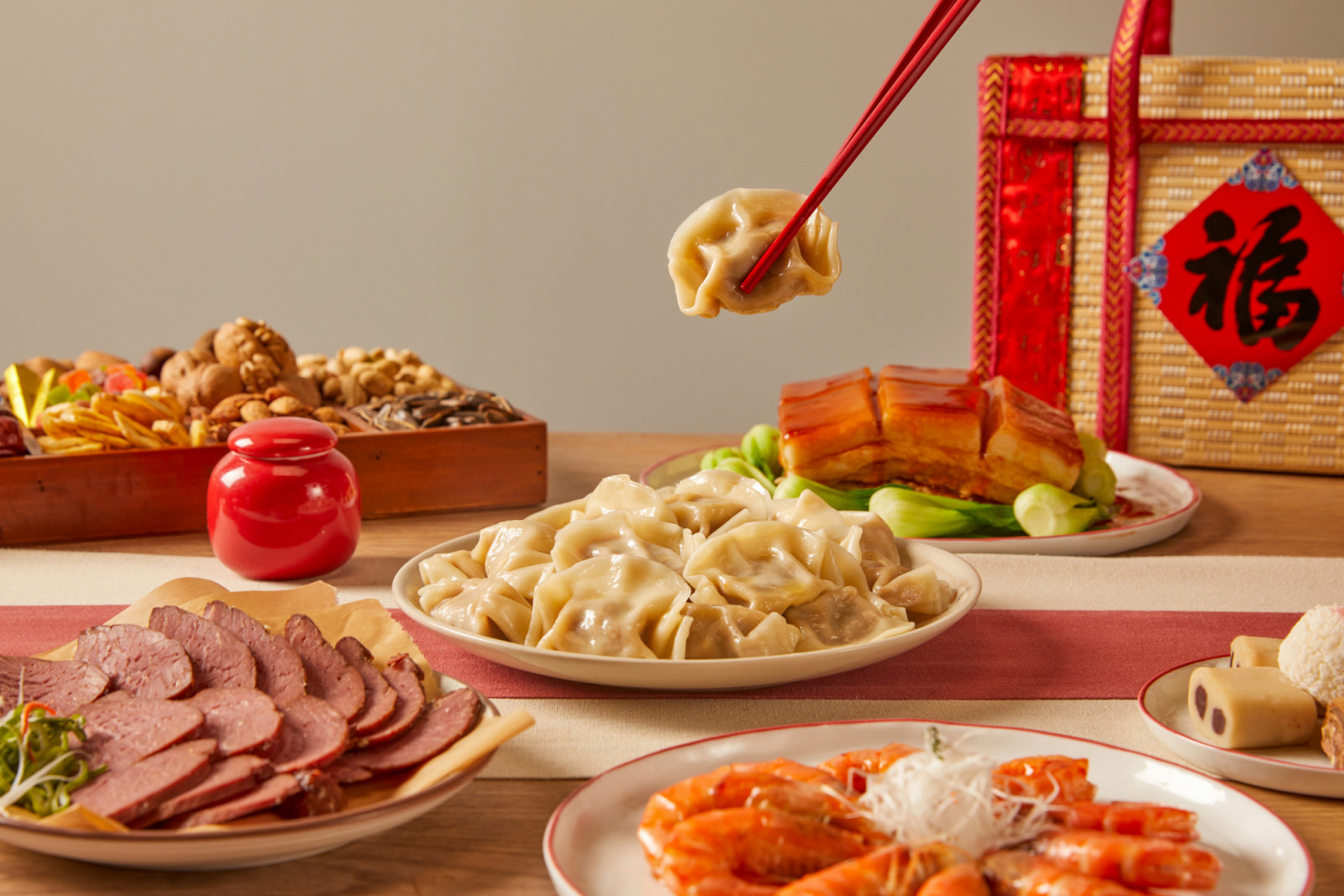 Chinese style festive atmosphere, wooden dining table, various snacks, pastries, lanterns, gifts, red envelopes, fish, Chinese food, dumplings(Translation:The text means auspicious and good luck) (ภาพ: CatherScarl / Getty Images)