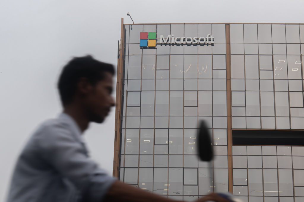 A man is riding his bike past an office building of Microsoft in Gurugram, in the outskirts of New Delhi, India, on July 19, 2024. Airlines, businesses, and various institutions are being affected due to a global Microsoft outage. Various flights around the world are being canceled, and flight operations that rely on Microsoft Systems are being affected. (Photo by Kabir Jhangiani/NurPhoto via Getty Images)